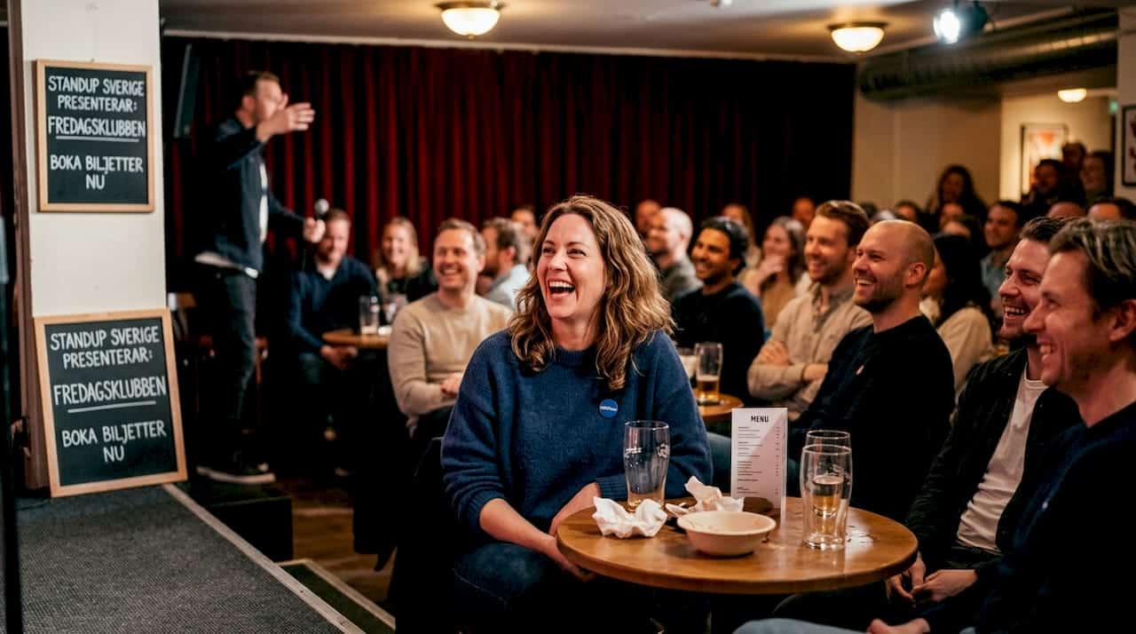 1774150696821_Audience-laughing-inside-comedy-club-basement-1