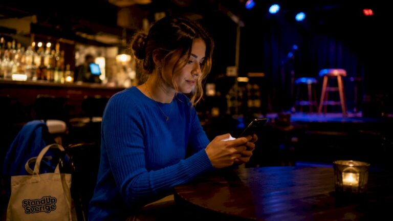En kvinna sitter på ett café och köper en biljett direkt i mobilen.