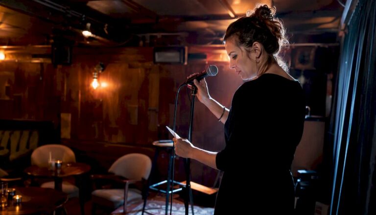 En kvinnlig konferencier gör sig redo på scenen och justerar mikrofonen inför kvällens standup.